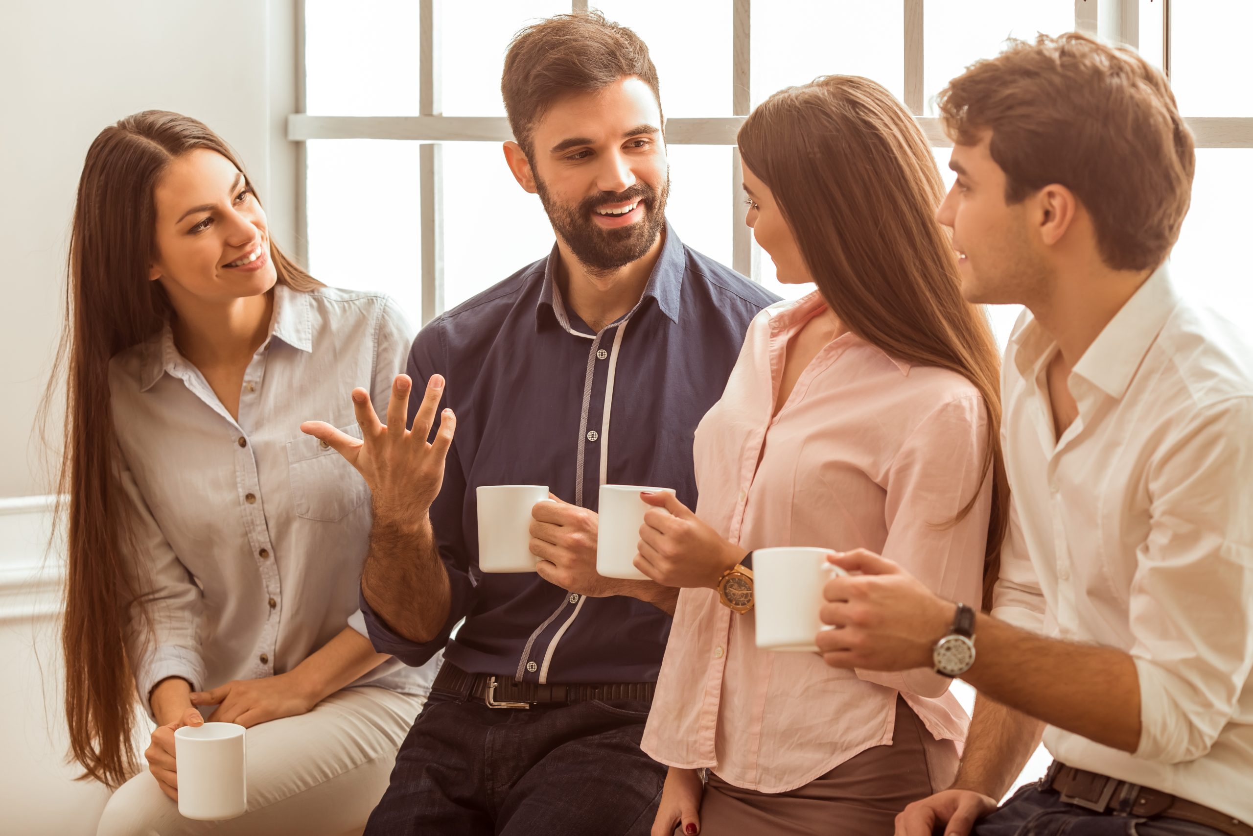 Group of young people Coffee break chat. Group of attractive business people, standing next to each other, holding a cups, smiling standing at the window